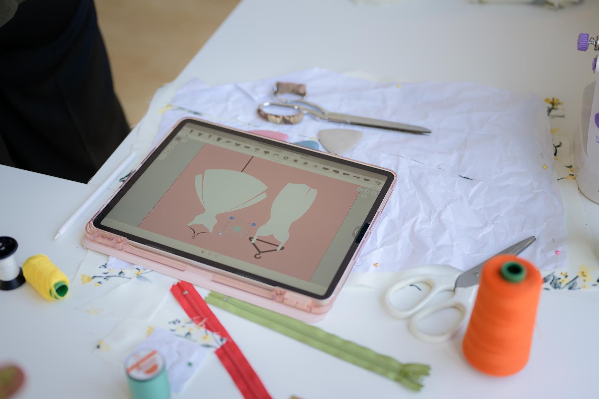 Studio founder digitizing a pattern on a tablet next to thread cards
